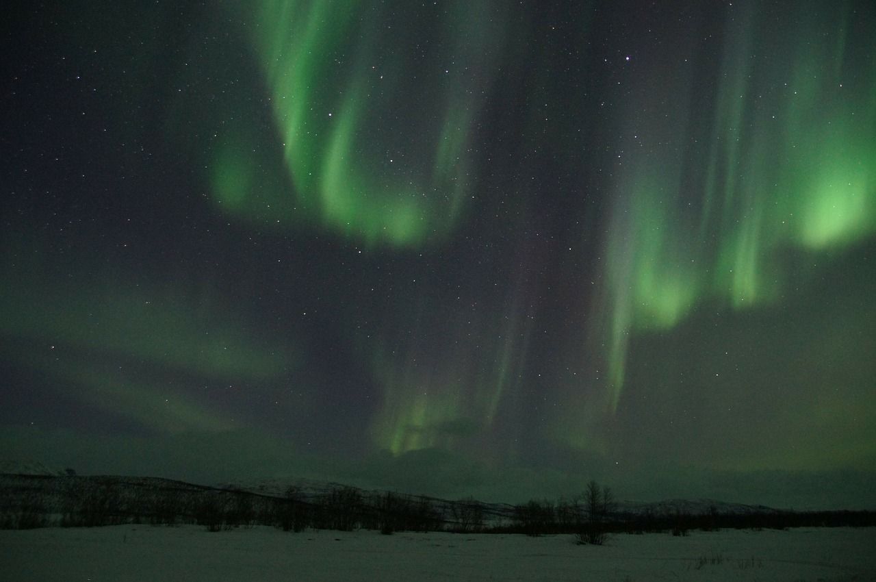 Aurora boreal con tonos verdes sobre cielo nocturno, fenómeno de luces del norte