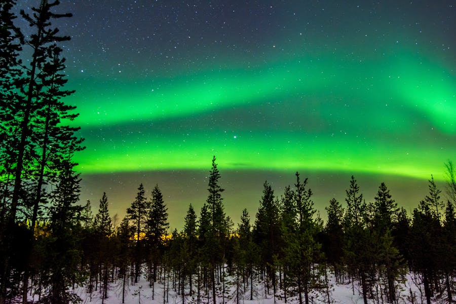 Aurora boreal sobre paisaje nevado, ejemplo de noche clara en Rovaniemi