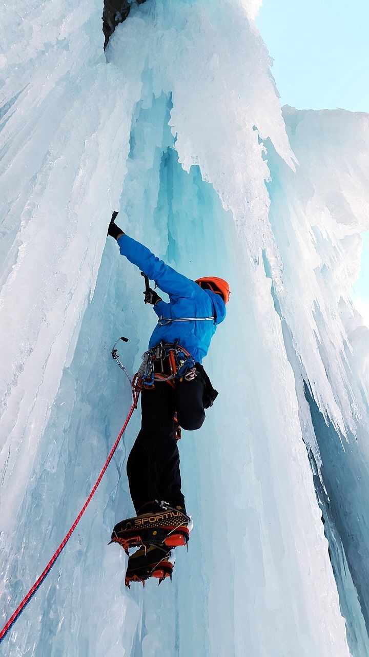 Escalador progresando con cuerda en pared de hielo vertical