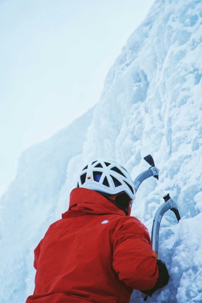 Participante asegurado ascendiendo pared de hielo