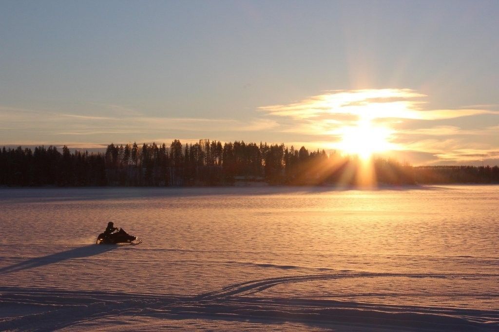 Aurora boreal sobre una moto de nieve en el Parque Nacional cerca de Rovaniemi